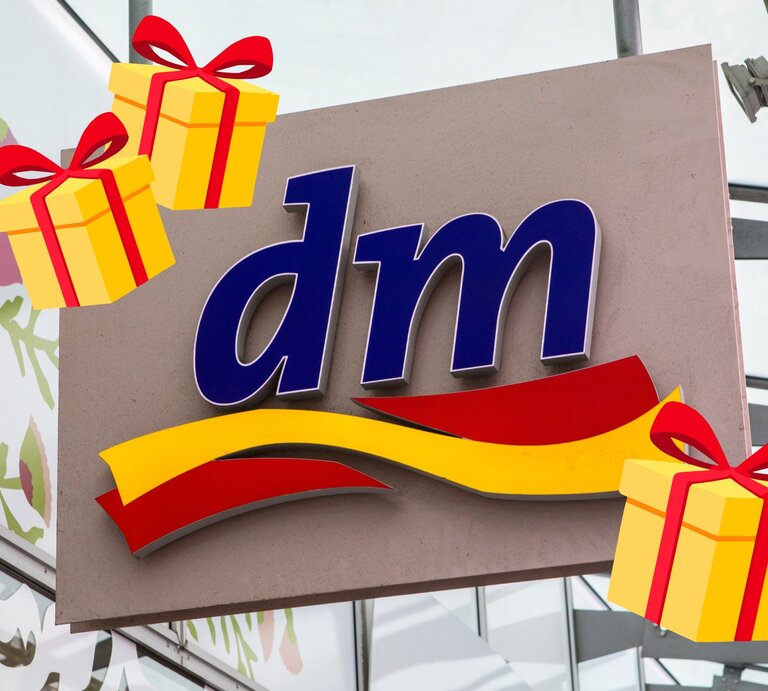 Das blau-rote dm-Logo auf einem Schild, umgeben von illustrativen gelben Geschenkpaketen mit roten Schleifen vor gläsernem Hintergrund. | © Collage: Adobe Stock/ chrisdorney, BILD der FRAU
