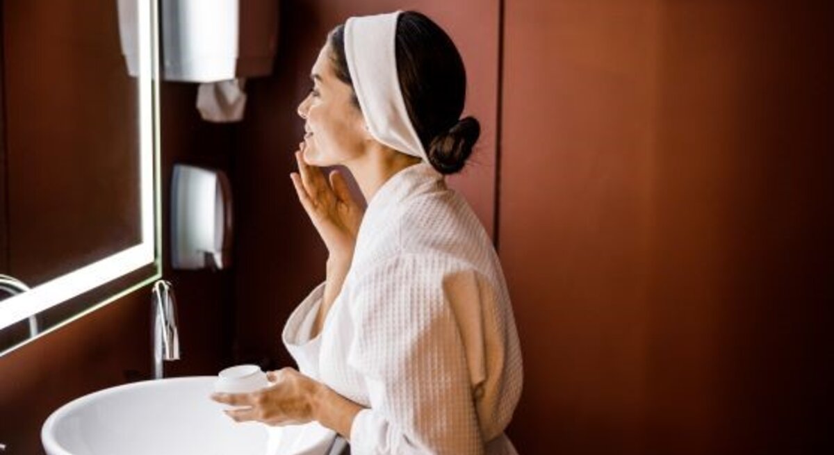 Frau führt vor Spiegel Beauty-Routine am Abend durch