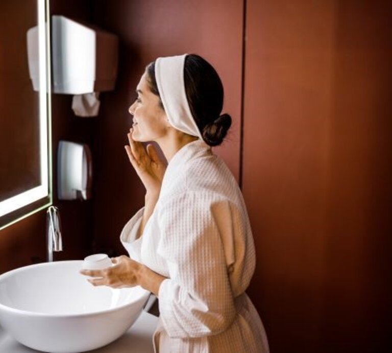 Frau führt vor Spiegel Beauty-Routine am Abend durch | © Shutterstock / Olena Yakobchuk