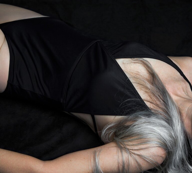 Körper einer Frau mit langen grauen Haaren, von der man nur den Torso von hinten in einem Badeanzug sieht. | © Getty Images /Andreas Kuehn