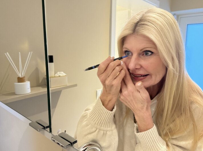 Topage-Model Renate Zott beim Anmalen der Augen mit Kajal vor dem Spiegel | © Renate Zott