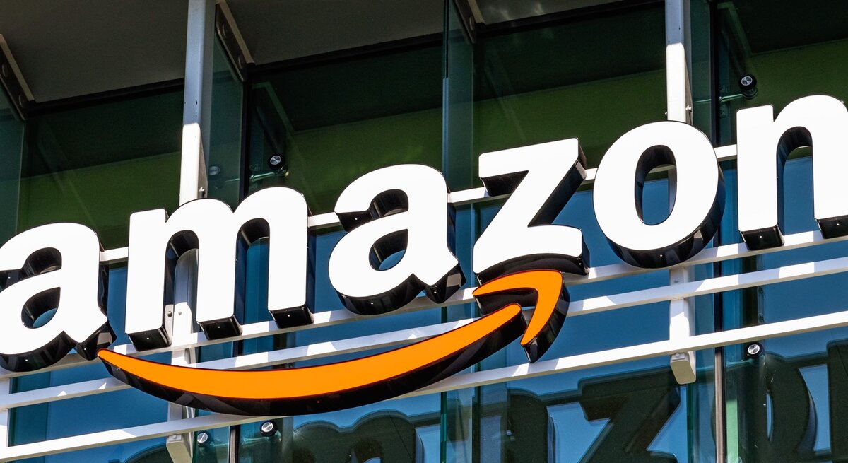 Nahaufnahme des bekannten Amazon-Schriftzugs mit orangem Pfeil auf Gebäudefront.
