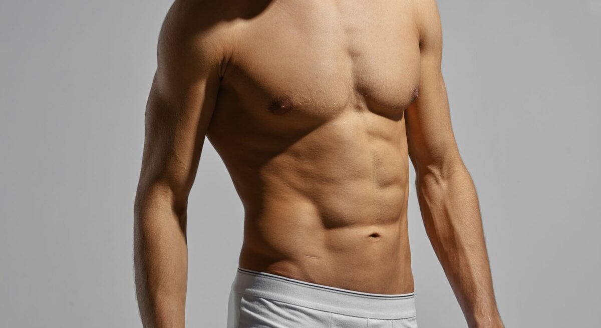 Muskulöser, nackter Oberkörper eines jungen Mannes, Gesicht und weiße Unterhose sind nur zum Teil zu sehen