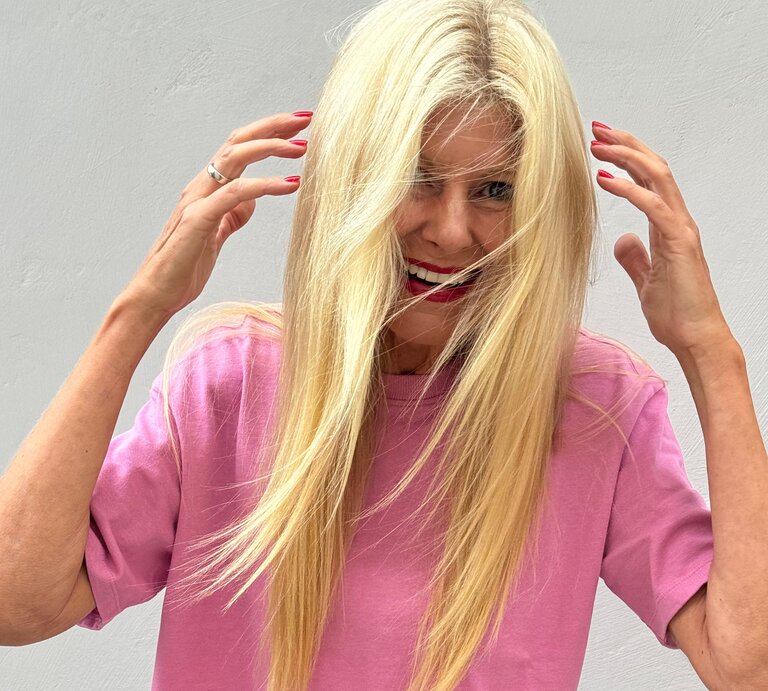 Lachende Renate Zott in pinkem Shirt streicht sich mit roten Fingernägeln die Haare aus dem Gesicht. | © Renate Zott