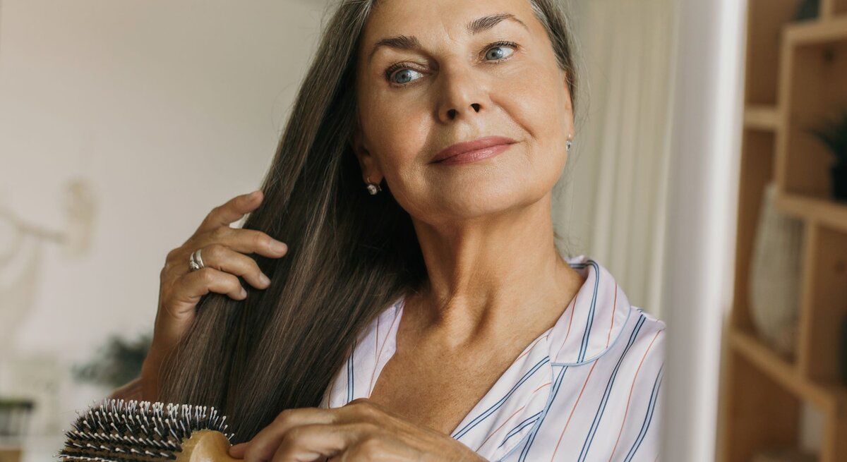Zu sehen ist eine mittlelalte Frau, die ihre Haare kämmt