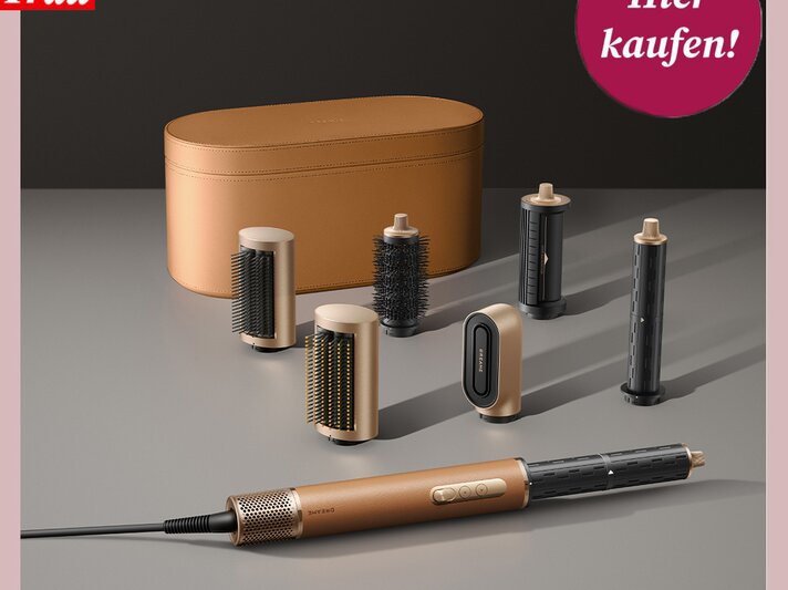 Haarstyling-Set mit goldenen Details, mehreren Bürstenaufsätzen und stilvoller, ockerfarbener Aufbewahrungstasche vor dunklem Hintergrund. | © Dreame