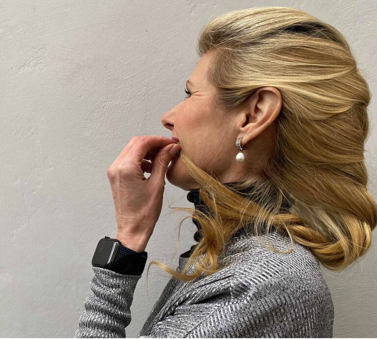 Frau mit blondem Haar, die eine elegante, seitlich geschwungene Frisur trägt. Ihr Haar ist sanft nach hinten gelegt und leicht geflochten. | © Renate Zott