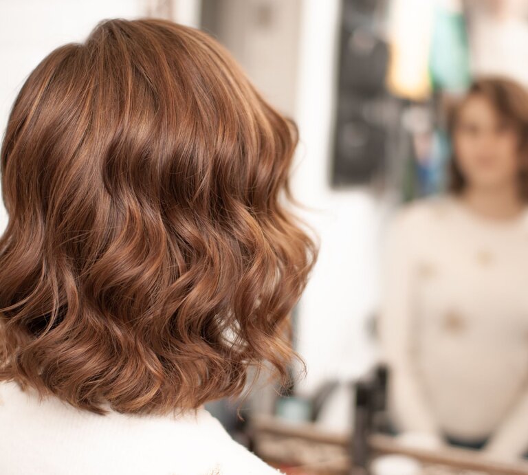 Frau mit Locken-Bob, der geschmeidig das Gesicht umspielt. Die sanften Wellen verleihen der Frisur Lebendigkeit und eine spielerische Note. | © Adobe Stock / Oksy001