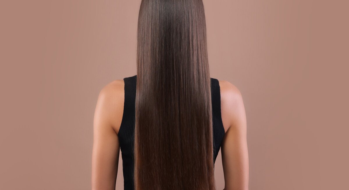 Zu sehen sind glänzende, glatte Haare vor einem beigen Hintegrund