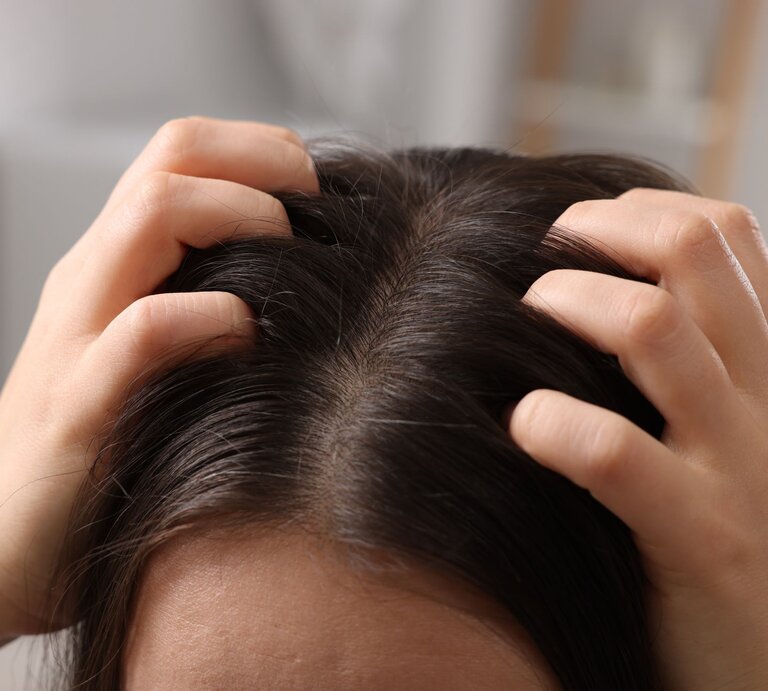 Eine Person mit dunklem Haar drückt ihre Fingerspitzen gegen die Kopfhaut, offenbar bei einer wohltuenden Kopfmassage. | © Shutterstock/New Africa
