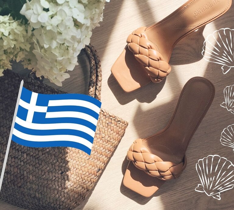 Sommerliche Szene mit Sandalen, Korbtasche und griechischer Flagge, umgeben von weißen Muschelgrafiken und zarten Blumen. | © Collage: bildderfrau.de; Canva