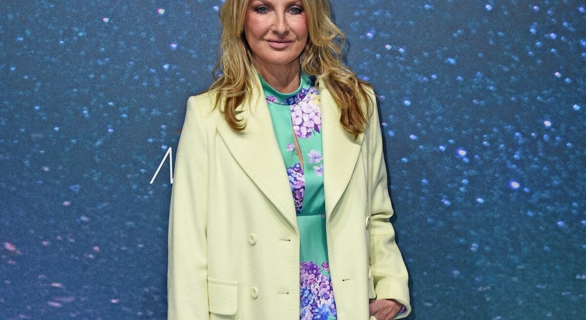Elegant gekleidete Frauke Ludowig mit welligem, blondem Haar trägt ein mintgrünes Kleid mit floralem Muster, hellgrünen Mantel und nudefarbene Pumps.