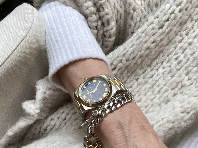 Anti-Aging-Accessoires: Handgelenk von Renate Zott mit eleganter Bi-Color-Armbanduhr und silbernem Kettchen ruht auf grob gestrickter, cremefarbener Wolldecke. | © Renate Zott