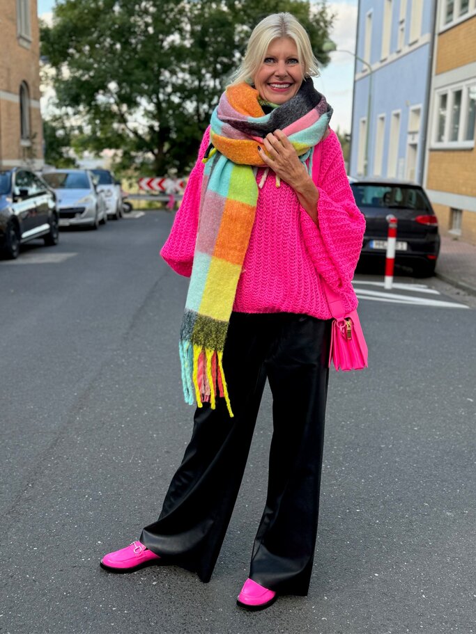 Modebewusste Reante Zott mit weitem Schal, pinken Loafern und schwarzer Hose kombiniert knallige Farben zu einem frischen Herbstlook. | © Renate Zott