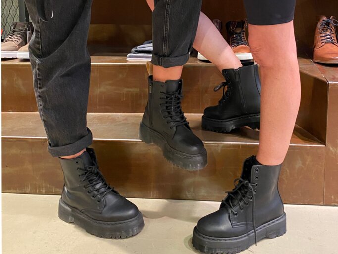 Trendige schwarze Plateau-Boots kombiniert mit lässiger Streetwear, fotografiert im Schuhgeschäft vor einem Regal mit Herrenschuhen. | © Renate Zott