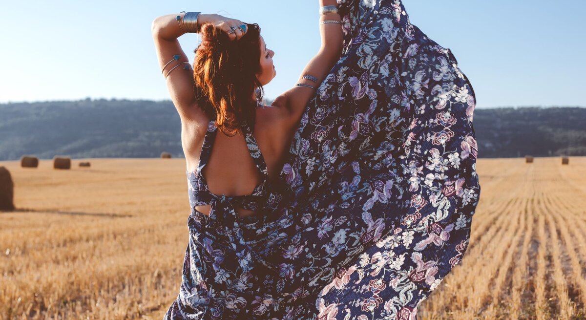 Zu sehen ist eine Frau von hinten, die ein florales, geblümtes Kleid trägt