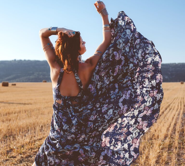 Zu sehen ist eine Frau von hinten, die ein florales, geblümtes Kleid trägt | © Shutterstock/Alena Ozerova