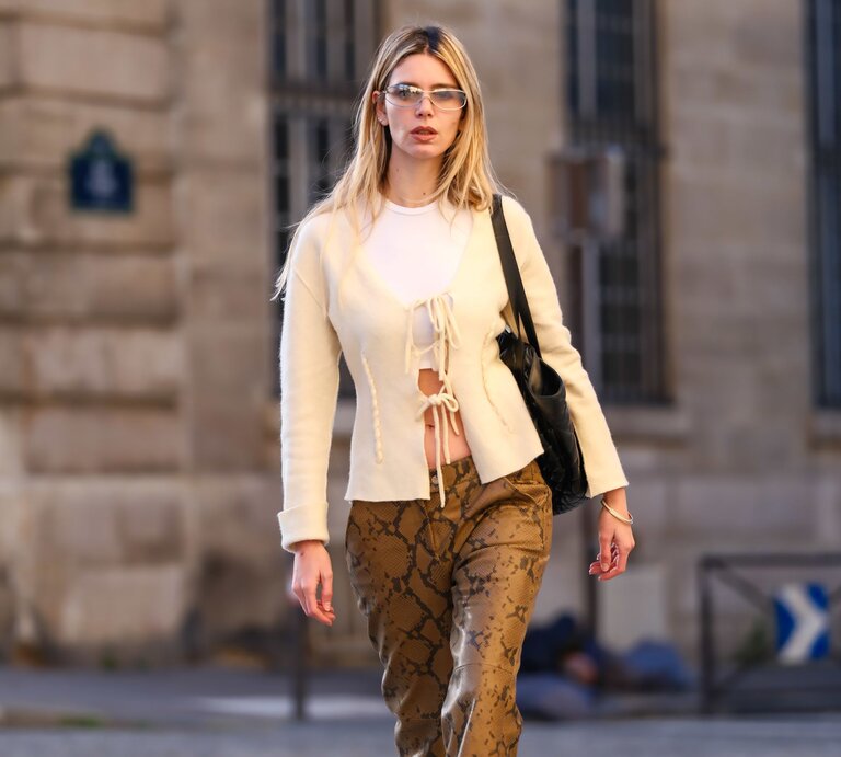 Zu sehen ist eine Frau mit einer gelben Strickjacke und Tiermusterhose | © GettyImages/Edward Berthelot 