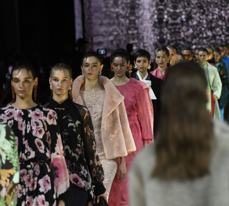Eine Reihe von Models in eleganter Designermode mit floralen Mustern, Pastelltönen und luxuriösen Stoffen läuft über den Laufsteg. | © IMAGO / Marja