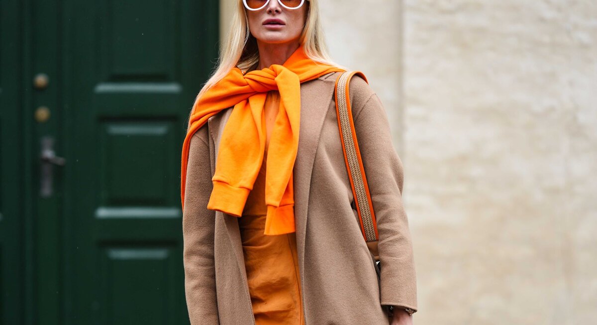 Zu sehen ist eine Frau in einem stylischen Streetstyle Outfit mit hohem Orangeanteil