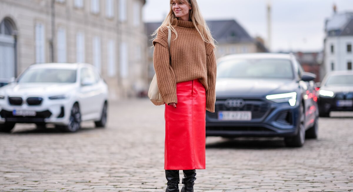 Streetstylefoto von Frau in rotem Lederrock. Zusätzlich trägt sie einen hellen Strickpullover mit Rollkragen