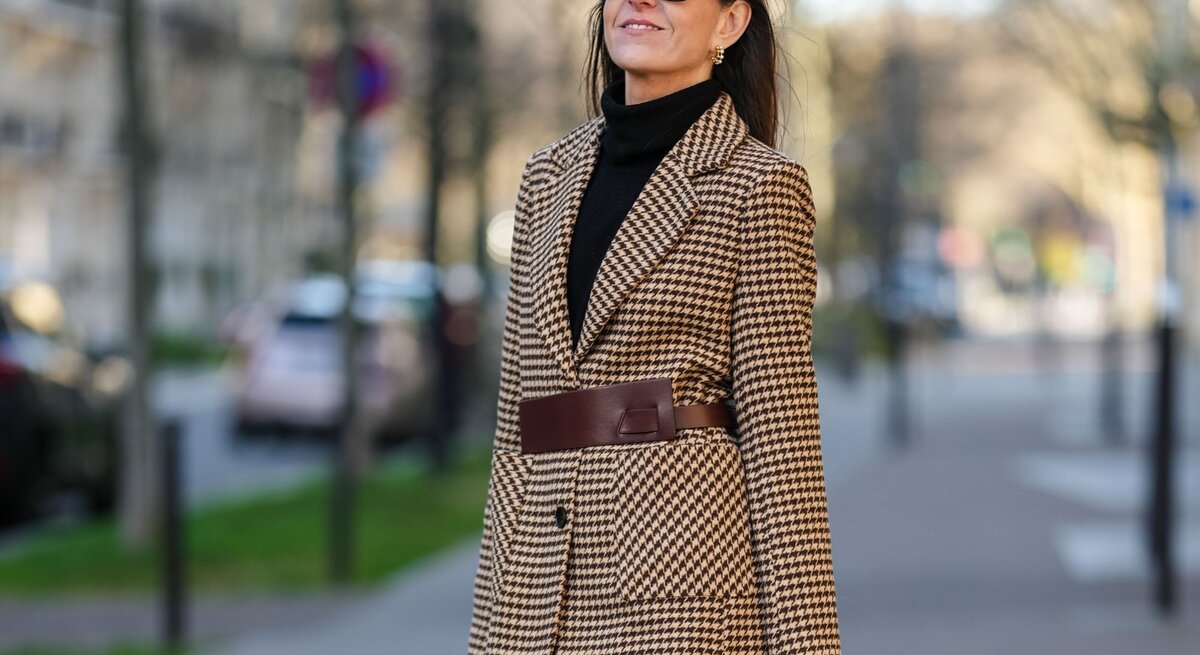 Zu sehen ist eine Frau mittleren Alters, die einen Blazer, einen Rollkragen und eine straight leg blue Jeans trägt