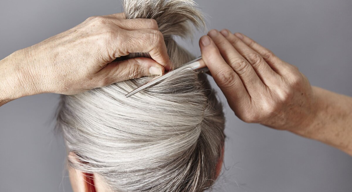 Zu sehen ist eine Frau mit grauen Haaren, die einen French Twist trägt