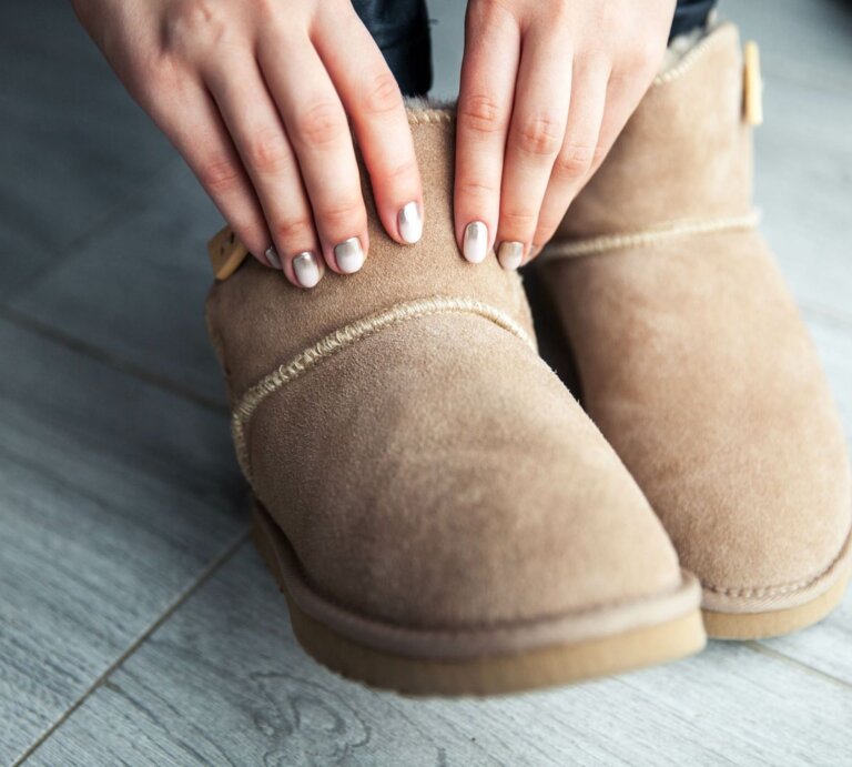 Zwei Hände greifen nach warmen, beigen Winterboots von Lidl mit heller Naht, auf grauem Laminatboden. | © Adobe Stock/ serbogachuk