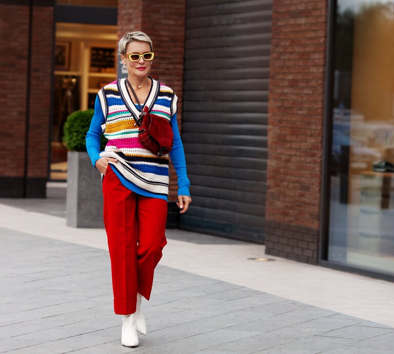 Frau in einem auffälligen bunten Outfit läuft die Straße entlang. | © Getty Images/ Anna Zhuk
