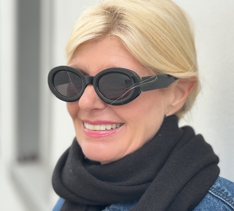 Nahaufnahme einer Frau, die eine auffällige, ovale Sonnenbrille trägt. Die Sonnenbrille hat breite, schwarze Rahmen und verleiht ihrem Look eine moderne, stilbewusste Note. | © Renate Zott
