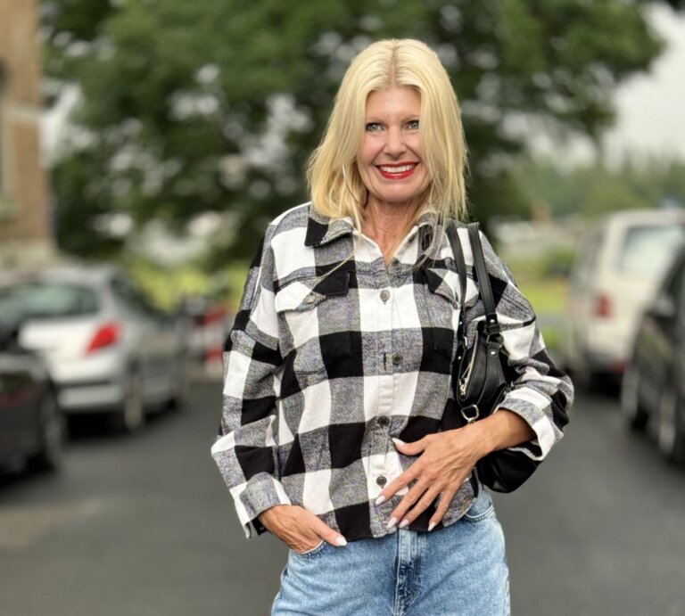 Frau mit blonden Haaren, die in einem lässigen, karierten Hemd in Schwarz-Weiß und einer hellen Jeans gekleidet ist.  | © Renate Zott