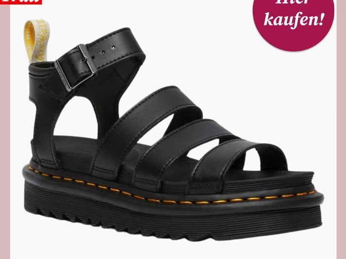 Schwarze, offene Sandale mit breiten Lederriemen, Schnalle und dicker Profilsohle, präsentiert vor neutralem Hintergrund. | © Dr. Martens