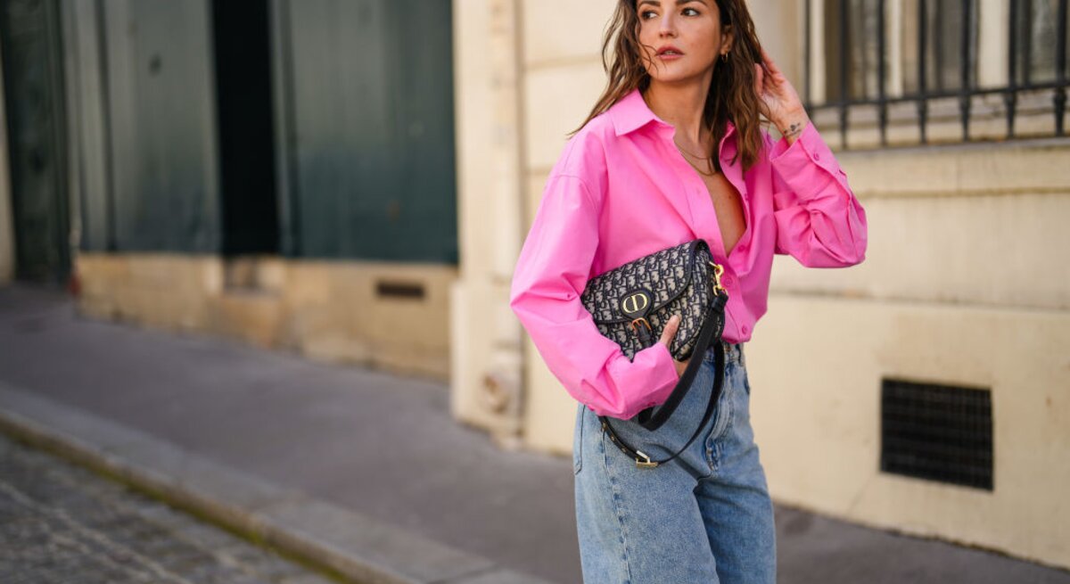 Zu sehen ist eine blonde Frau mit pinker Bluse und Jeans Bermudas.