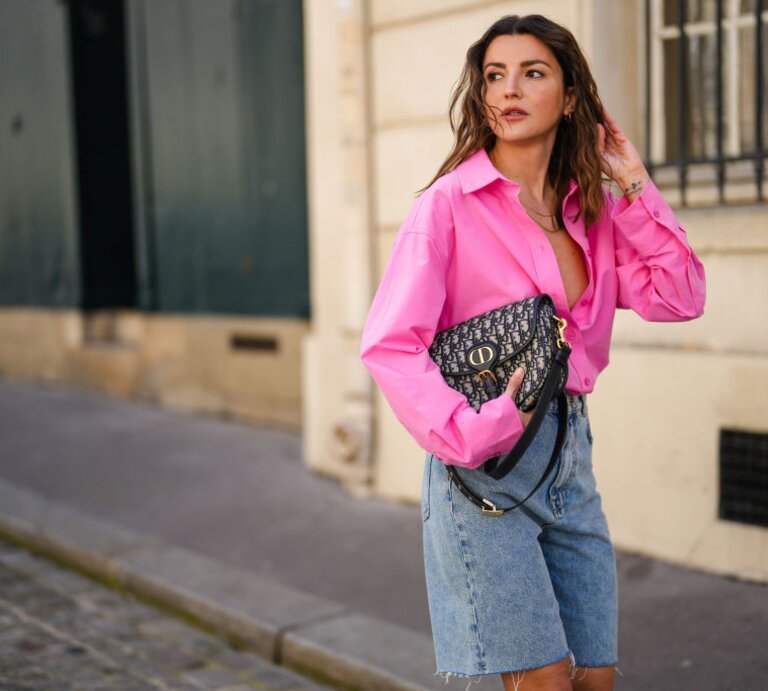 Zu sehen ist eine blonde Frau mit pinker Bluse und Jeans Bermudas. | © GettyImages/Edward Berthelot 
