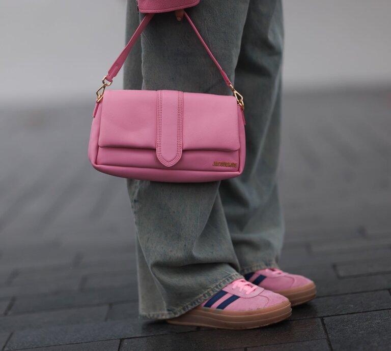 Detailaufnahme einer rosa Handtasche mit goldener Schnalle, getragen zu lässiger Jeans und farblich abgestimmten Sneakers. | ©  Jeremy Moeller/Getty Images