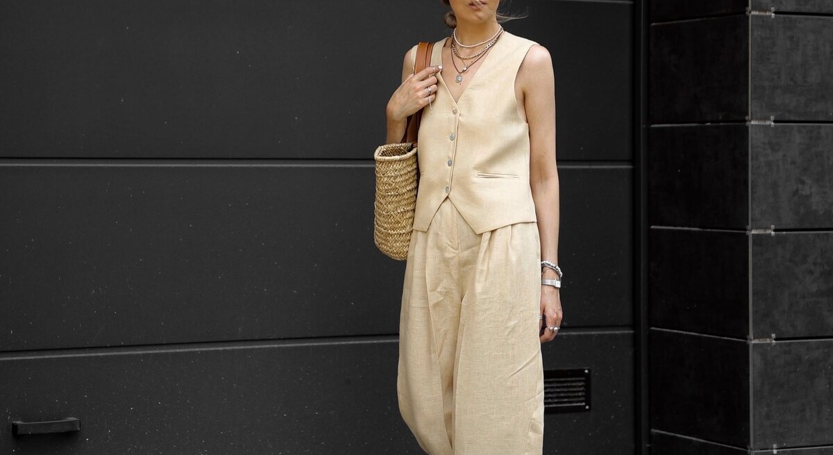 Zu sehen ist eine blonde Frau, die eine beige Weste, sowie eine Palazzohose trägt.