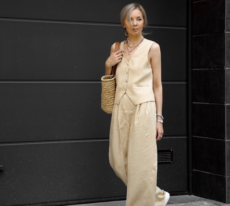 Zu sehen ist eine blonde Frau, die eine beige Weste, sowie eine Palazzohose trägt. | © Shutterstock/Eugenia Lytvyn