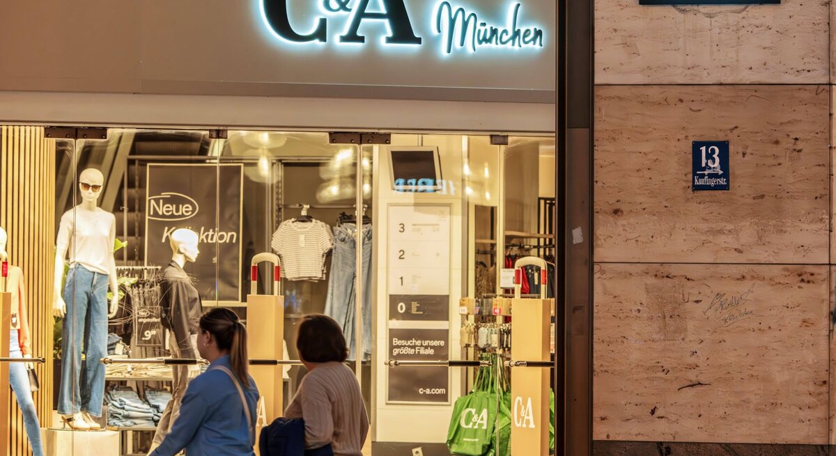 C&A-Filiale in München bei Nacht, mit Schaufensterpuppen und Passanten.