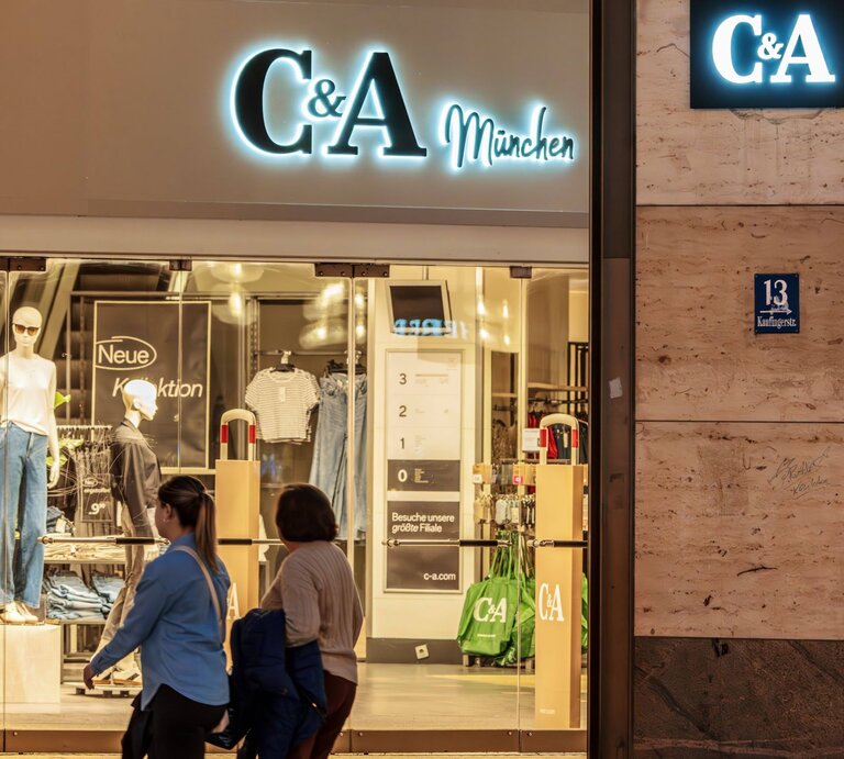 C&A-Filiale in München bei Nacht, mit Schaufensterpuppen und Passanten. | © IMAGO / Wolfgang Maria Weber