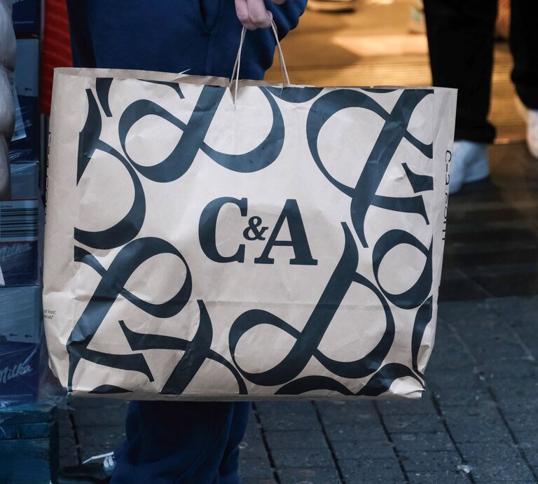 Detailaufnahme einer Einkaufstasche mit C&A-Schriftzug, im Hintergrund unscharfe Passanten. | © IMAGO / Michael Gstettenbauer