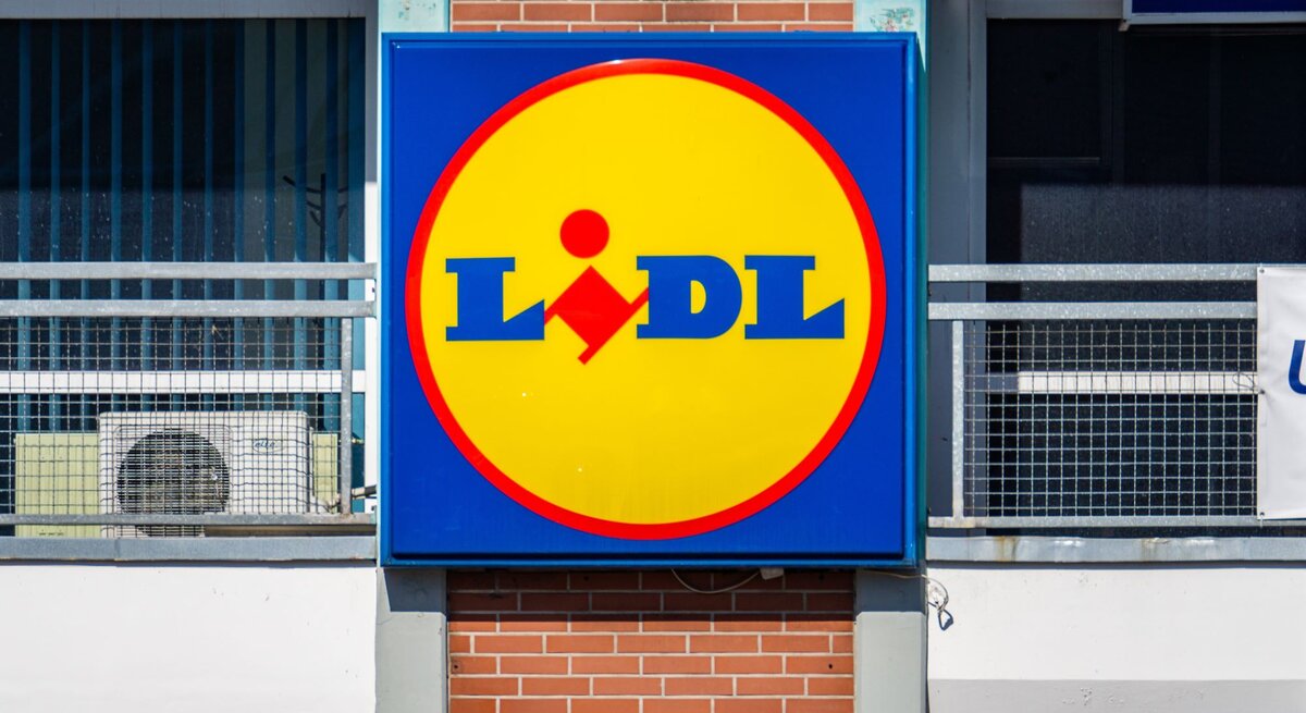 Großes Lidl-Logo in Gelb und Blau an der Außenwand eines Gebäudes mit roten Ziegeln.