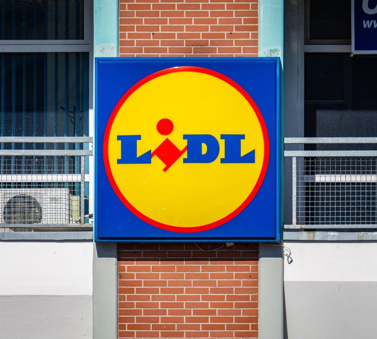 Großes Lidl-Logo in Gelb und Blau an der Außenwand eines Gebäudes mit roten Ziegeln. | © Adobe Stock/ Lukasz Czajkowski