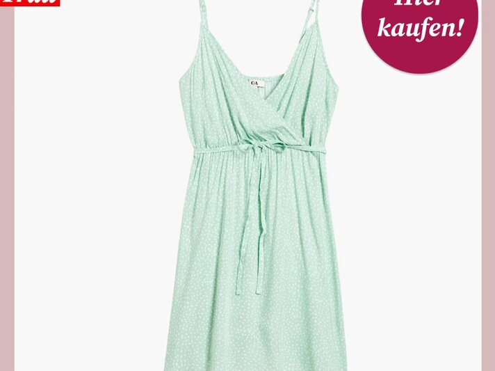 Das Bild zeigt ein sommerliches, mintgrünes Kleid mit zarten weißen Punkten. Das Kleid hat dünne Träger, einen V-Ausschnitt und eine taillierte Passform mit einem Bindeband in der Taille. Es ist locker geschnitten und fällt fließend, was es zu einer leichten und luftigen Option für warme Tage macht. Das Kleid ist vor einem einfarbigen, pastellrosa Hintergrund platziert. In der oberen linken Ecke des Bildes befindet sich das Logo "Bild der Frau" in Weiß auf einem roten Hintergrund, und in der oberen rechten Ecke ist ein kreisförmiges, bordeauxrotes Etikett mit der weißen Aufschrift "Hier kaufen!". | © C&A