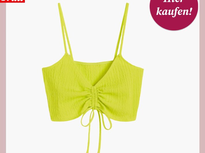 Ein leuchtend neongelbes Bikinioberteil im Crinkle-Look mit Spaghettiträgern und Raffung in der Mitte, die mit Schnüren gebunden ist. Über dem Bild steht das Logo „Bild der Frau“ und ein pinkfarbener Kreis mit der Aufschrift „Hier kaufen!“. Der Hintergrund ist einfarbig in einem zarten Rosa gehalten. | © H&M