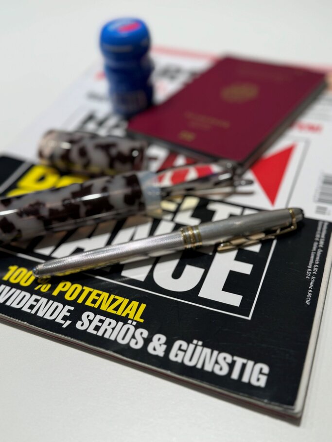 Sammlung von Gegenständen, die typischerweise für die Reise vorbereitet werden: ein deutscher Reisepass, ein Magazin, Stifte und eine Lesebrille.  | © Renate Zott
