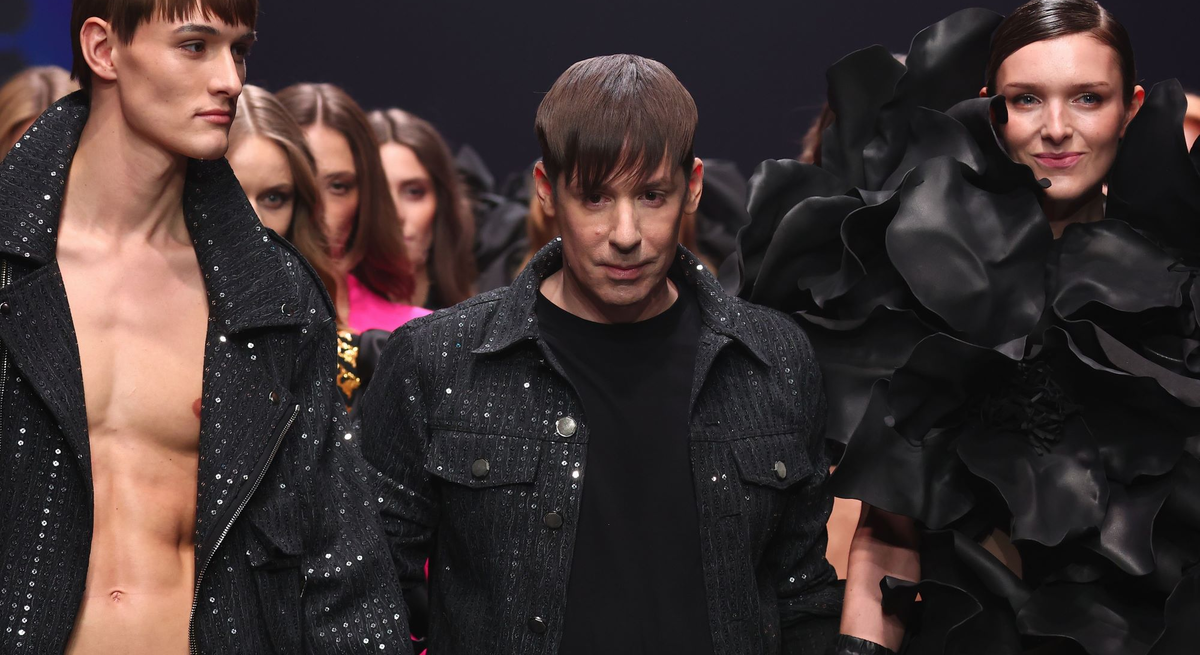 Designer Kilian Kerner mit braunem Pony schreitet mit Models in extravaganten schwarzen und glitzernden Outfits über den Laufsteg.