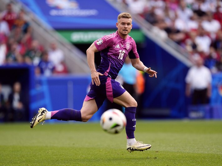 Fußballspieler Maximilian Mittelstädt im lila Deutschlandtrikot sprintet während eines Spiels auf einem Stadionrasen, der Ball vor ihm. | © dpa Pictures