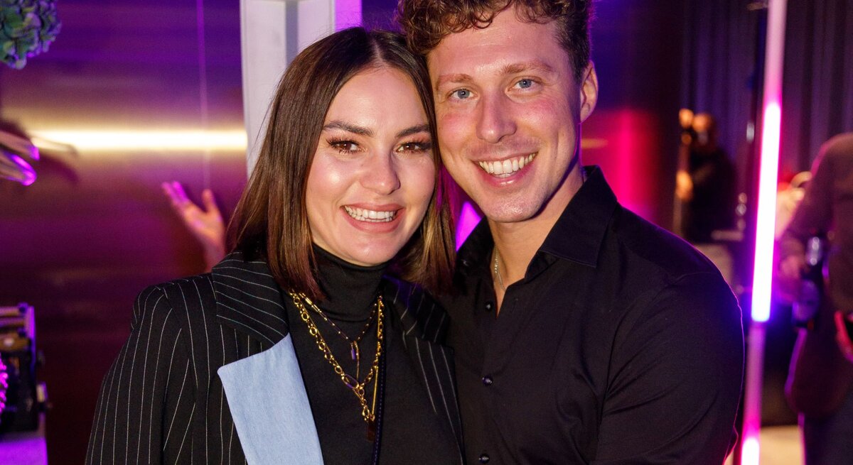 Renate Lusin und Valentin Lusin lächeln eng umschlungen in die Kamera, umgeben von pink-violettem Partylicht und stilvoller Clubatmosphäre.