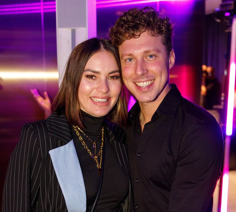 Renate Lusin und Valentin Lusin lächeln eng umschlungen in die Kamera, umgeben von pink-violettem Partylicht und stilvoller Clubatmosphäre. | © Joshua Sammer/Getty Images