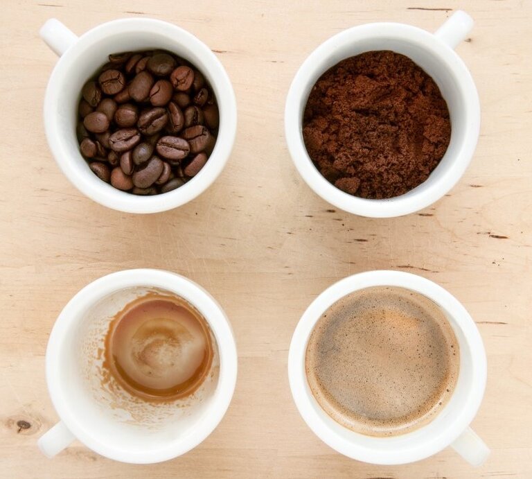 Vier weiße Tassen zeigen Bohnen, Pulver, frischen Kaffee und Kaffeereste als Phasen der Kaffeezubereitung von oben. | © Getty Images/ Nico De Pasquale Photography